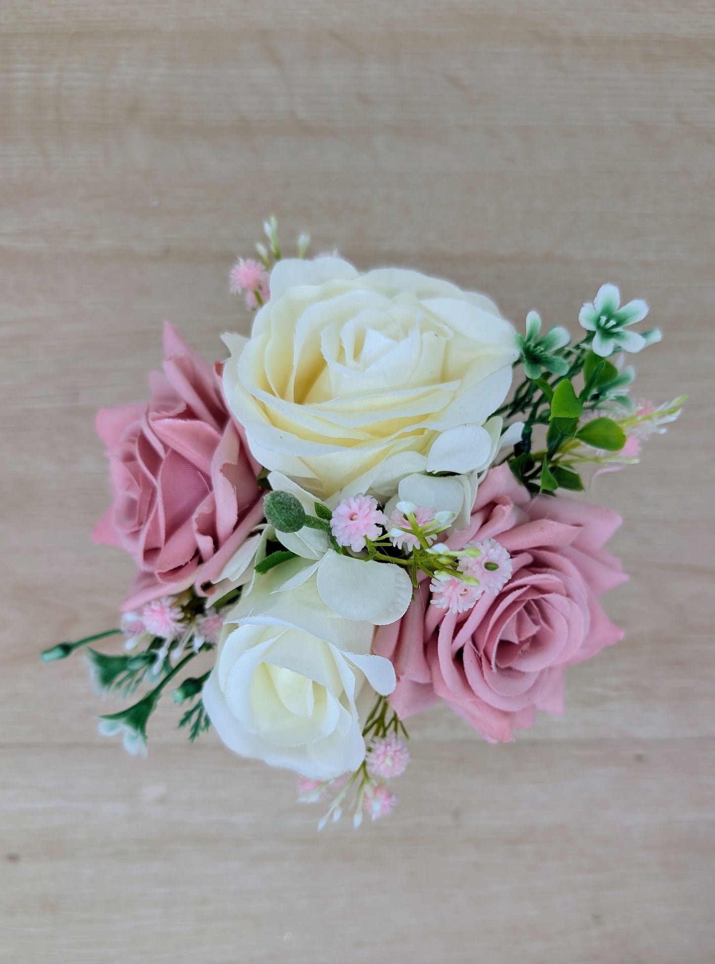 Bouquet of pink and white artificial flowers on a wooden surface