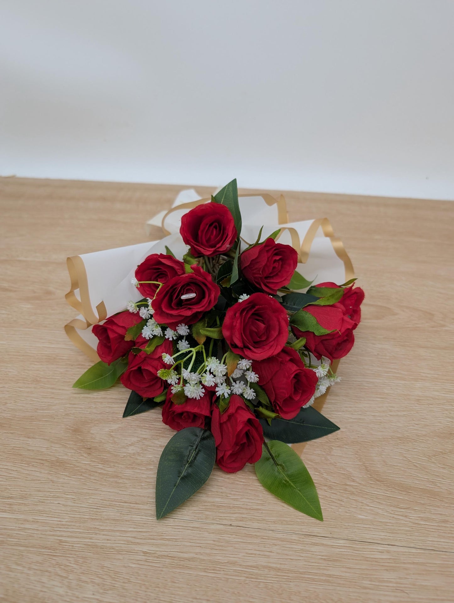 Bouquet of red roses with green leaves on a wooden surface