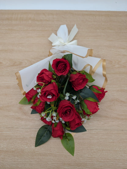 Bouquet of red roses with green leaves on a wooden surface