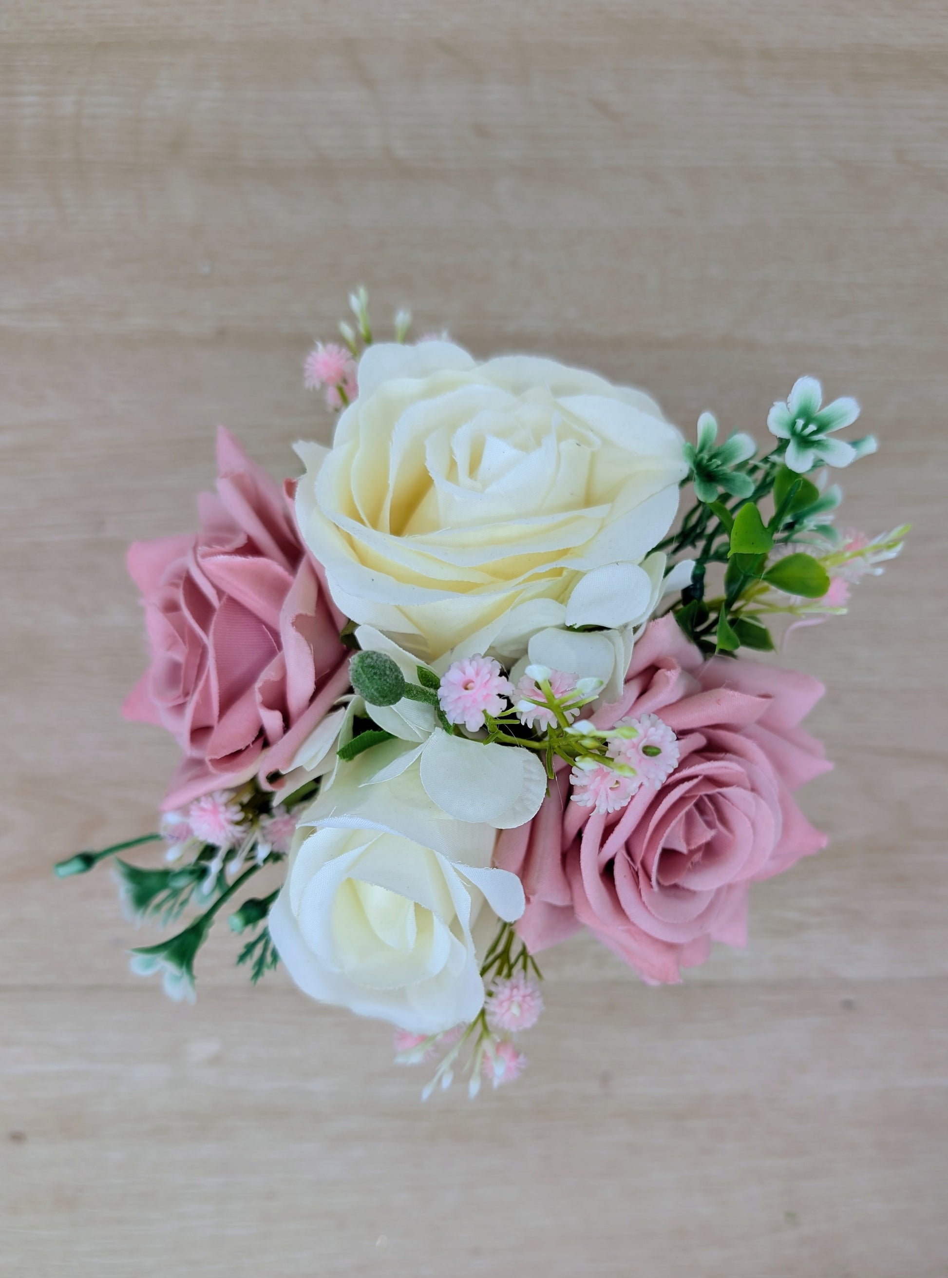 Bouquet of pink and white artificial flowers on a wooden surface
