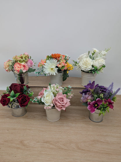 Set of six small potted floral arrangements on a wooden surface with a white background