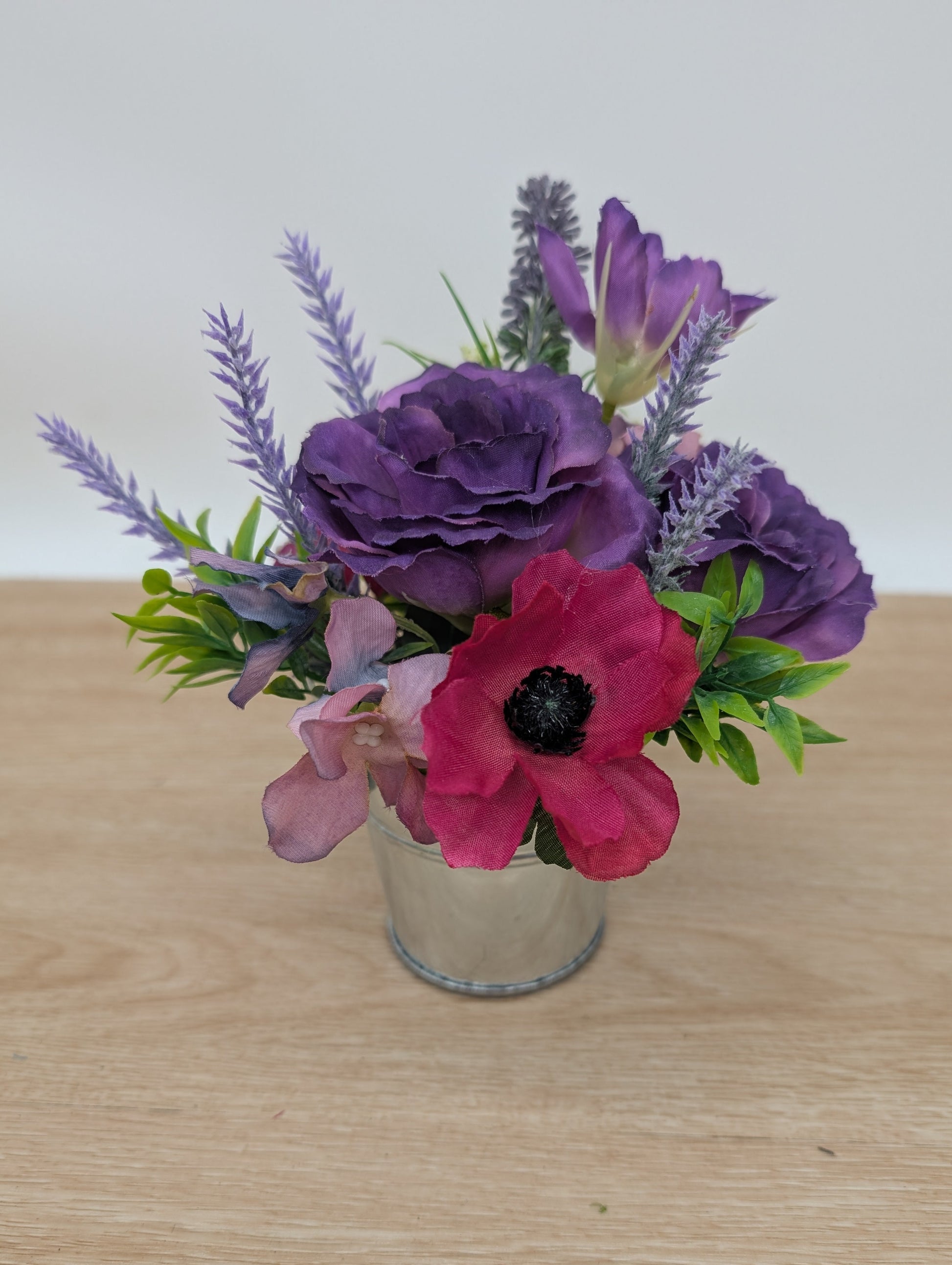 Floral arrangement with purple and pink flowers in a clear vase on a wooden surface.