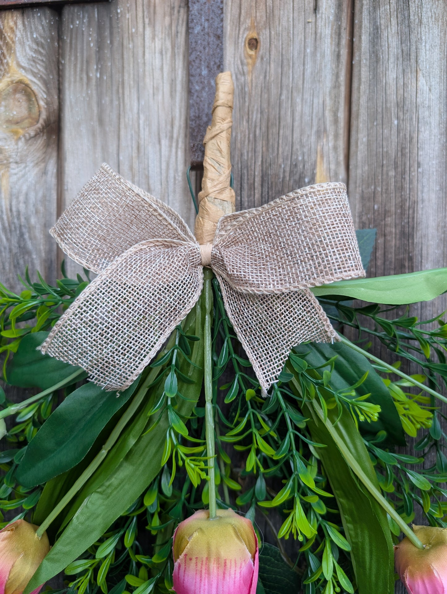 Decorative floral arrangement with a burlap bow against a wooden background